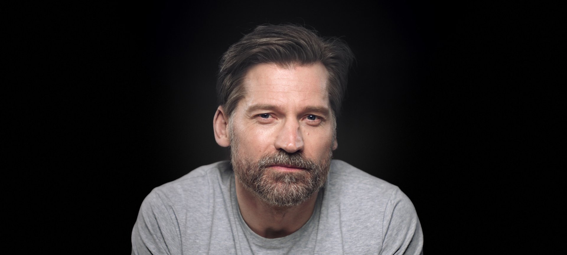 Portrait photo of Nicolaj Coster Waldau in front of black background.